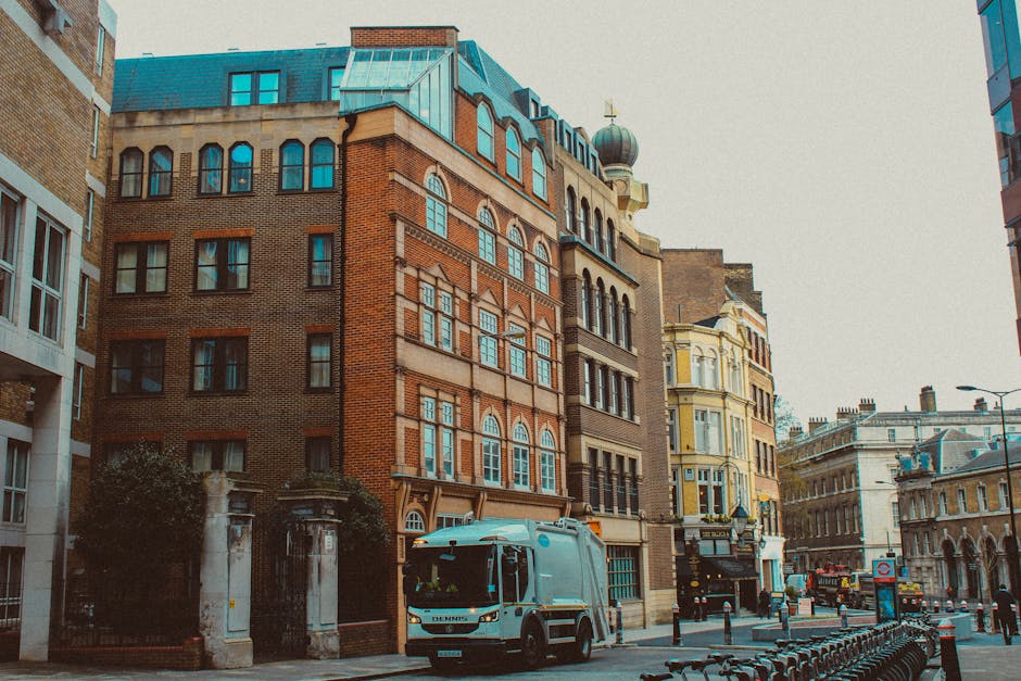 A photograph capturing a city street scene in Bloomsbury, featuring a white delivery van parked adjacent to a multi-storey brick building with large, arched windows and decorative architectural detail